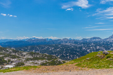 Mountains with snow in Austria, summer landscape. The European Alps in the distance, blue sky and green grass in foreground. Travel and summer concept.