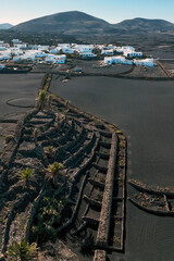 White buildings, town among volcanic black mountains and lava formations in Lanzarote, Canary Islands.