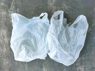 Two translucent white plastic bags on the floor. Plastic waste.