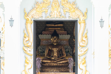 golden buddha statue inside ornate thai temple framed by gilded naga motifs