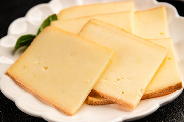 Raclette cheese portion slicing natural product tasty snack fresh delicious gourmet food background on the table rustic top view copy space