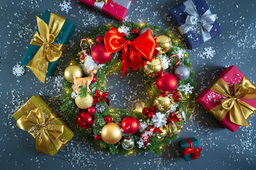 Decorated Christmas wreath and gift boxes on a gray background with snow.