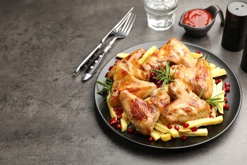 Delicious grilled chicken wings with french fries served on grey table, closeup. Space for text