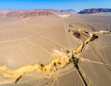 Aerial view of a vast desert landscape with a canyon and distant mountains
