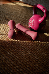 Various weights placed on a woven mat in a warm and inviting workout space during the afternoon light