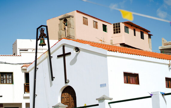 A small white colored Catholic chirch with an ancient bell tower.