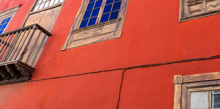 A rustic house with red bright walls and old wooden shutters on the windows. - Powered by Adobe