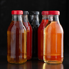 Bottles of various colorful beverages arranged together against a dark background in a modern setting