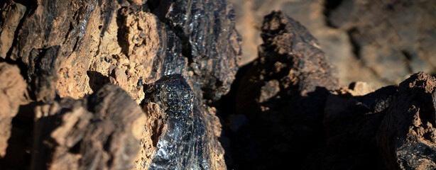 Lava formations, stones, black basalt in the rocks closeup on a volcano terrain.