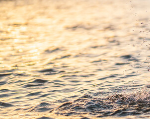 Drops of water fallling to the ocean at sunset closeup.
