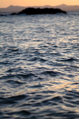 A small island in the beautiful ocean with small waves in the evening  at sunset.