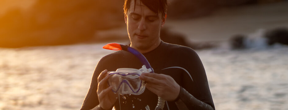 A man is preparing for diving in the ocean at sunset.