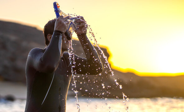 A man is preparing for diving in the ocean at sunset.