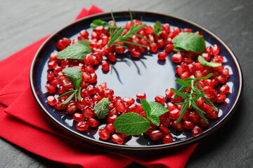 Christmas food. Pomegranate seeds, mint and rosemary on dark textured table, closeup