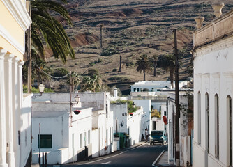 Roand among small cozy white buildings against the backdrop of mountains on a sunny day.
