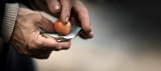 Hands of a poor person closep, holding banknotes.