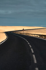 Fototapeta premium An asphalt road among desert with sandy dunes.