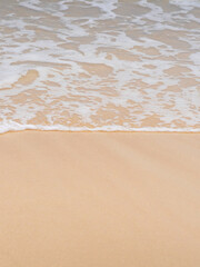 A sandy beach on the coastline of the ocean with clear water with small waves.