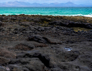 Black lava formations on the coast of the Atlantic ocean with a clean blue water.