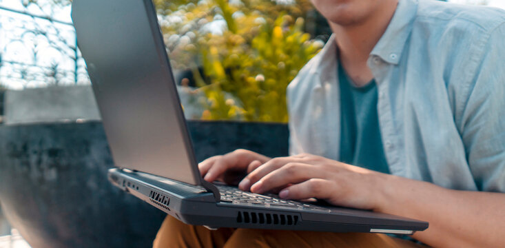A man works on a laptop outdoors, hands on a keyboard closeup. - Powered by Adobe