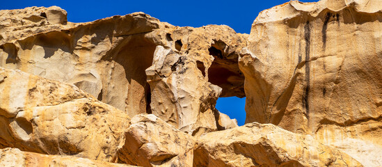 A rock, desert sandy formations, a natural arch Arco de las Penitas in the daylight.