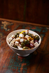 Green and kalamata olives and feta cheese on rustic wooden background. Soft focus.	