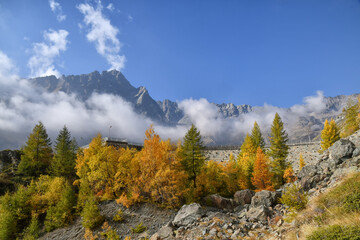 Paesaggio autunnale montano con foreste colorate e alte vette tra le nuvole