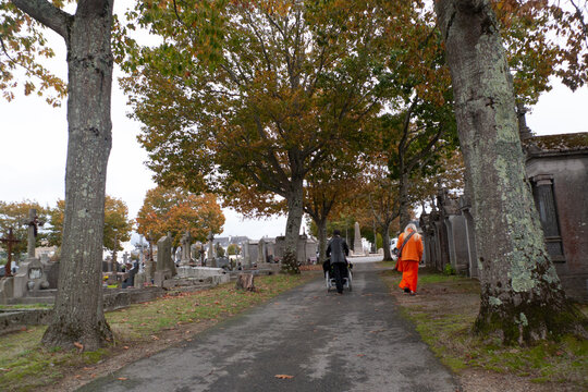 Assembl&eacute;e; Foule endeuill&eacute;e; Cercueil en bois clair; Tombes; Arbres d&eacute;nud&eacute;s; Feuillage d'automne; Fleurs artificielles