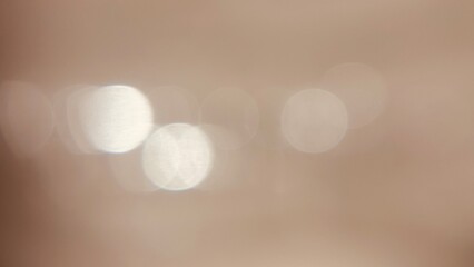 A soft, out-of-focus beige background with gentle circular bokeh light patterns.