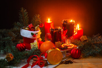 Glasses of mulled wine, burning candles, christmas stocking, christmas balls, pine branches, gifts...