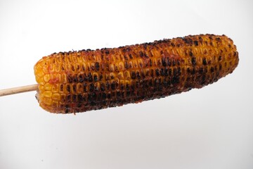 Charred and smoky grilled corn on the cob served on a stick, isolated against a white background, ideal for food and BBQ themes.
