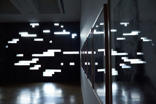 Interior of dark empty room with creative design: bright sunlight passing through holes of different size located on one wall, other wall decorated with mirrors, floor covered with brown tile