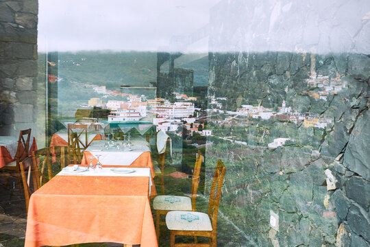 Picturesque view of lovely coastal town with colorful buildings reflected in panoramic window of family restaurant