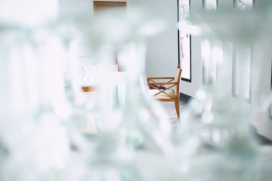 Fototapeta Interior of lovely restaurant with panoramic windows and light furniture, view through row of wine glasses