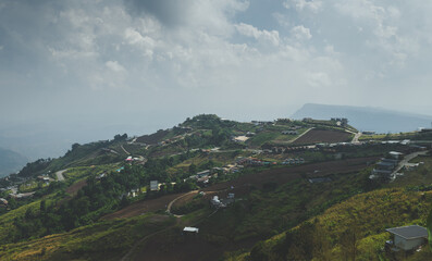 Hilly farmland with cloudy sky and green terrain