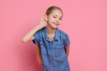 Girl showing hand to ear gesture on pink background