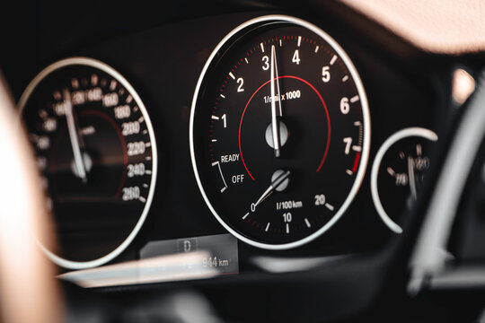 Car dashboard showing tachometer and speedometer while driving