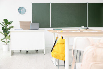 Green chalkboard, desks and chairs in classroom. Mockup for design