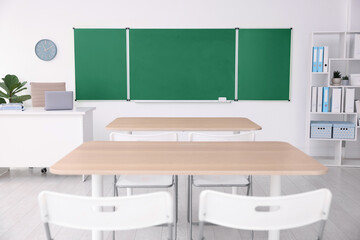 Green chalkboard, desks and chairs in classroom. Mockup for design