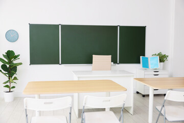 Green chalkboard and stylish furniture in classroom. Mockup for design