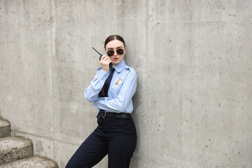 Police officer talking on radio near wall outdoors