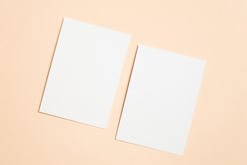 Fototapeta premium Two blank white sheets of paper placed on a soft peach background, creating a minimalistic and clean aesthetic, ideal for mockup designs and creative projects