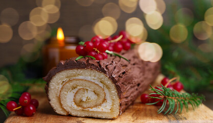 Delicious Yule log (traditional Christmas cake) with redcurrant and fir tree branches on table,...