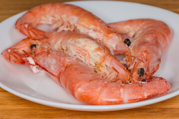 Boiled unshelled king prawns on dish, front view close-up