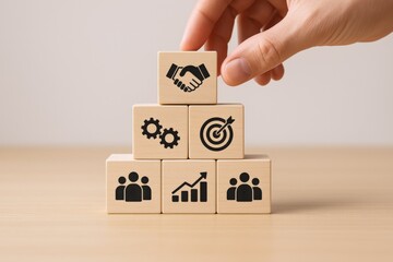 Business strategy concept: Hand stacking wooden blocks with partnership, teamwork, goals, and growth icons