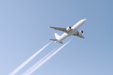 Obraz premium Airplane Ascending into Blue Sky with Contrails, Symbolizing Travel and Modern Aviation Technology