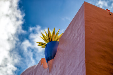 Blue Vase on a Pink Wall and Blue and White Sky Above.