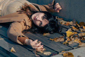 Caucasian young female lying on wooden deck surrounded by autumn leaves