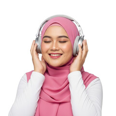 A young muslim woman wearing a pink hijab and white top enjoys music through silver headphones with eyes closed isolated on transparent background
