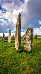 Ancient stone circle standing tall on green grass beneath a cloudy, dramatic sky
